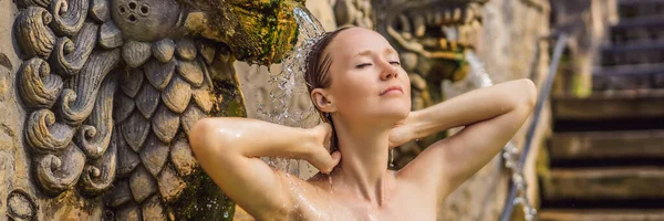 Mujer joven en banjar de aguas termales. El agua termal se libera de la boca de estatuas en una fuente termal en Banjar, Bali, Indonesia BANNER, FORMATO LARGO — Foto de Stock