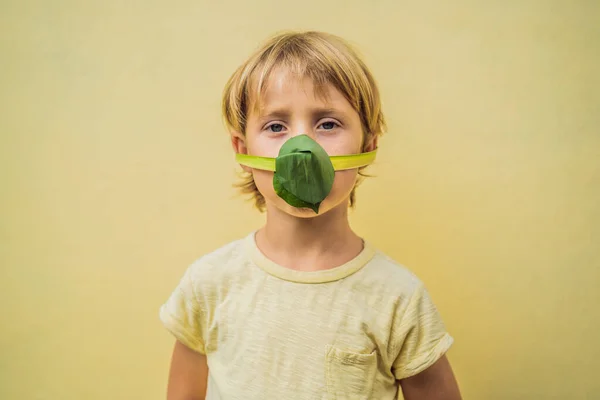 El niño se hizo una máscara facial de las hojas para protegerse de la contaminación del aire. Purificación de aire para niños concepto. Los árboles purifican el concepto de aire — Foto de Stock