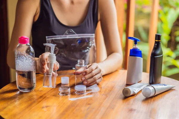 Travel kit for transporting cosmetics on an airplane. Cosmetics are ready to be poured into small bottles. A woman shifts cosmetics to take with her — Stock Photo, Image