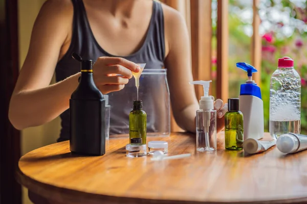 Travel kit for transporting cosmetics on an airplane. Cosmetics are ready to be poured into small bottles. A woman shifts cosmetics to take with her