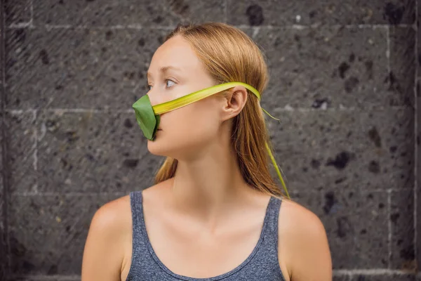 La mujer se hizo una máscara facial de las hojas para protegerse de la contaminación del aire. Concepto de purificación de aire. Los árboles purifican el concepto de aire — Foto de Stock