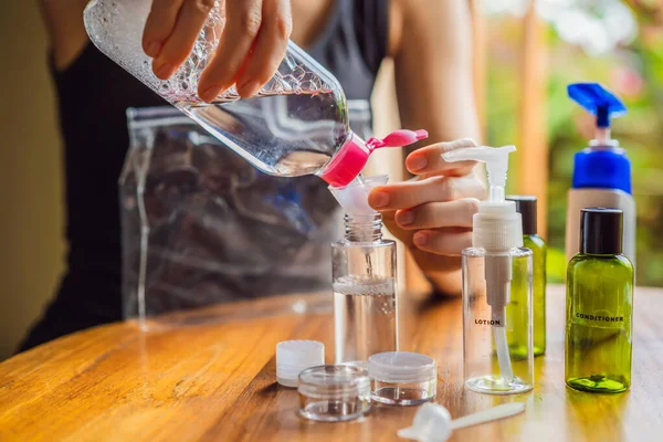 Kit de viaje para transportar cosméticos en un avión. Los cosméticos están listos para ser vertidos en botellas pequeñas. Una mujer cambia los cosméticos para llevar con ella —  Fotos de Stock