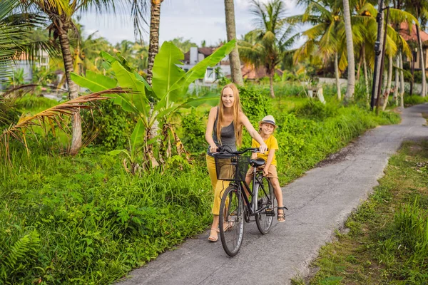 Moeder en zoon fietsen op een rijstveld in Ubud, Bali. Reis naar Bali met kids concept — Stockfoto