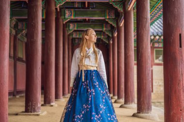 Kore Sarayı 'nda Hanbok Ulusal Kore elbisesi içinde genç beyaz kadın turist. Kore konseptine seyahat. Ulusal Kore giysileri. Turistler için eğlence - ulusal Kore kıyafetleri deniyor