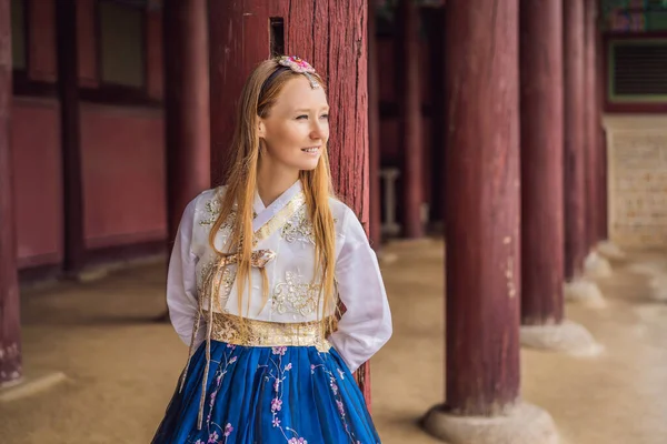 Jovem turista caucasiana em hanbok vestido coreano nacional no palácio coreano. Viajar para a Coreia conceito. Roupas nacionais coreanas. Entretenimento para turistas - experimentando roupas nacionais coreanas — Fotografia de Stock