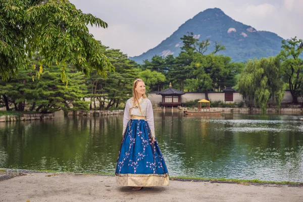 Jonge Kaukasische vrouwelijke toerist in hanbok nationale koreaanse jurk in Koreaanse paleis. Reis naar Korea concept. Nationale Koreaanse kleding. Entertainment voor toeristen - nationale Koreaanse kleding passen — Stockfoto