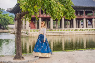 Kore Sarayı 'nda Hanbok Ulusal Kore elbisesi içinde genç beyaz kadın turist. Kore konseptine seyahat. Ulusal Kore giysileri. Turistler için eğlence - ulusal Kore kıyafetleri deniyor