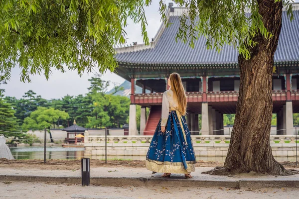 Jeune touriste caucasienne en robe coréenne nationale hanbok au palais coréen. Voyage en Corée concept. Vêtements nationaux coréens. Divertissement pour les touristes - essayer des vêtements nationaux coréens — Photo
