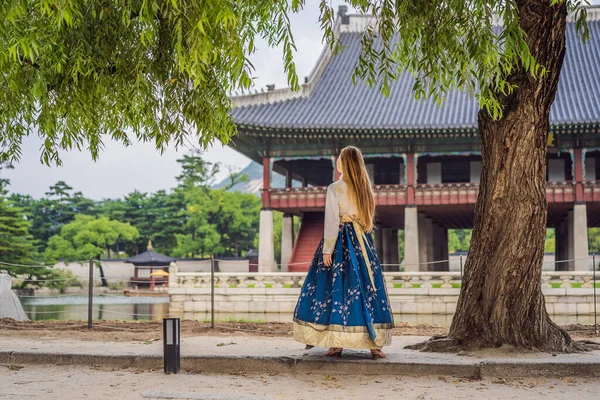 Kore Sarayı 'nda Hanbok Ulusal Kore elbisesi içinde genç beyaz kadın turist. Kore konseptine seyahat. Ulusal Kore giysileri. Turistler için eğlence - ulusal Kore kıyafetleri deniyor