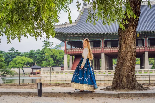 Kore Sarayı 'nda Hanbok Ulusal Kore elbisesi içinde genç beyaz kadın turist. Kore konseptine seyahat. Ulusal Kore giysileri. Turistler için eğlence - ulusal Kore kıyafetleri deniyor — Stok fotoğraf