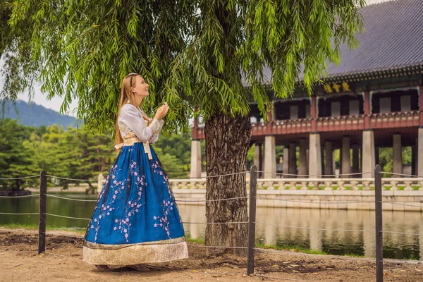 Kore Sarayı 'nda Hanbok Ulusal Kore elbisesi içinde genç beyaz kadın turist. Kore konseptine seyahat. Ulusal Kore giysileri. Turistler için eğlence - ulusal Kore kıyafetleri deniyor — Stok fotoğraf