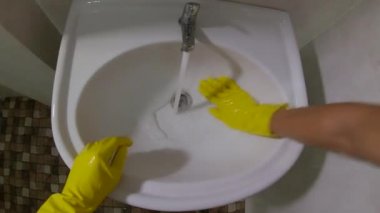 Bakış açısına göre, sarı eldivenli adam lavaboyu yıkıyor.