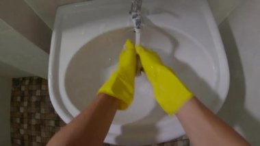 Bakış açısına göre, sarı eldivenli adam lavaboyu yıkıyor.