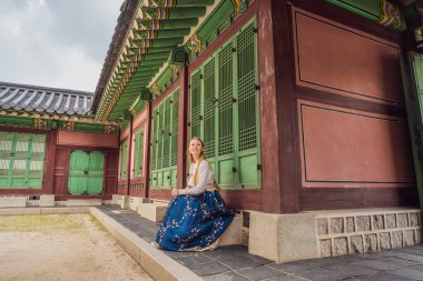 Kore Sarayı 'nda Hanbok Ulusal Kore elbisesi içinde genç beyaz kadın turist. Kore konseptine seyahat. Ulusal Kore giysileri. Turistler için eğlence - ulusal Kore kıyafetleri deniyor