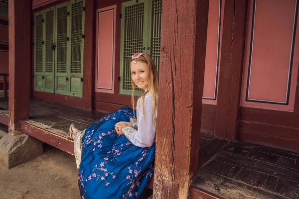 Ung kaukasisk kvinnlig turist i hanbok nationalkoreansk klänning på koreanska palatset. Res till Korea konceptet. Nationella koreanska kläder. Underhållning för turister - provar på nationella koreanska kläder — Stockfoto