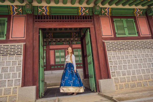 Giovane turista donna caucasica in hanbok abito coreano nazionale a palazzo coreano. Viaggio in Corea concetto. Abbigliamento nazionale coreano. Intrattenimento per i turisti - provare abbigliamento nazionale coreano — Foto Stock