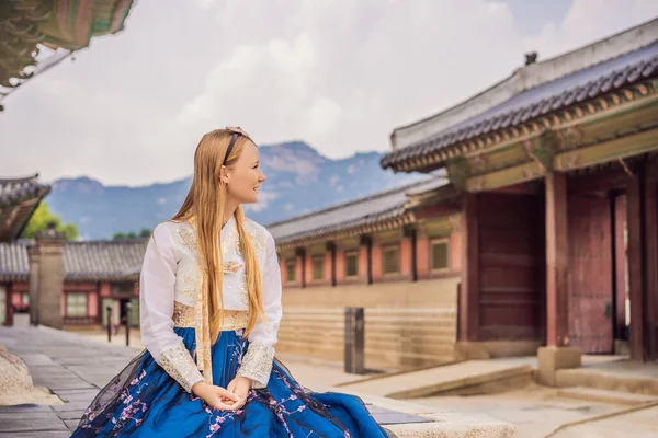 Jovem turista caucasiana em hanbok vestido coreano nacional no palácio coreano. Viajar para a Coreia conceito. Roupas nacionais coreanas. Entretenimento para turistas - experimentando roupas nacionais coreanas — Fotografia de Stock