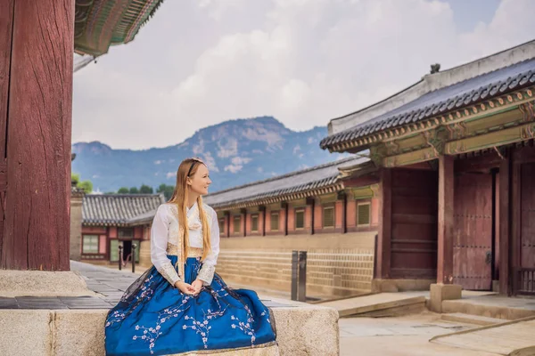 Jovem turista caucasiana em hanbok vestido coreano nacional no palácio coreano. Viajar para a Coreia conceito. Roupas nacionais coreanas. Entretenimento para turistas - experimentando roupas nacionais coreanas — Fotografia de Stock