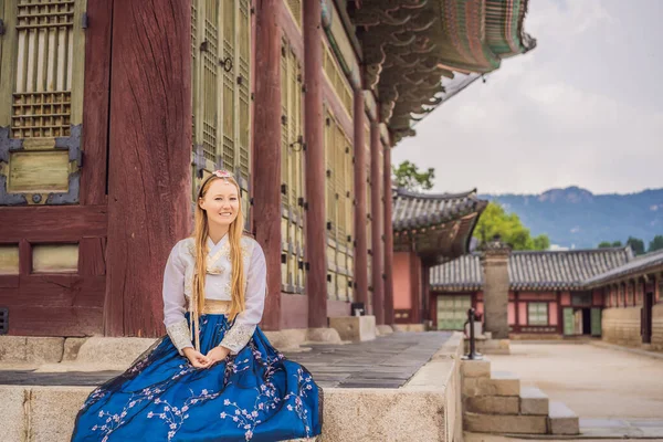 Jovem turista caucasiana em hanbok vestido coreano nacional no palácio coreano. Viajar para a Coreia conceito. Roupas nacionais coreanas. Entretenimento para turistas - experimentando roupas nacionais coreanas — Fotografia de Stock