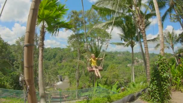 Slow motion shot van kleine jongen swing op grote schommels in een tropische omgeving — Stockvideo