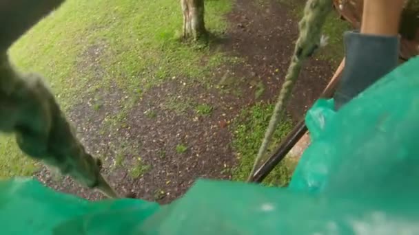Point de vue d'un homme dans un harnais de sécurité qui grimpe sur un chemin en cime des arbres dans un parc d'aventure forestière. Il grimpe sur le sentier des hautes cordes. Centre de loisirs extérieur avec activités d'escalade 