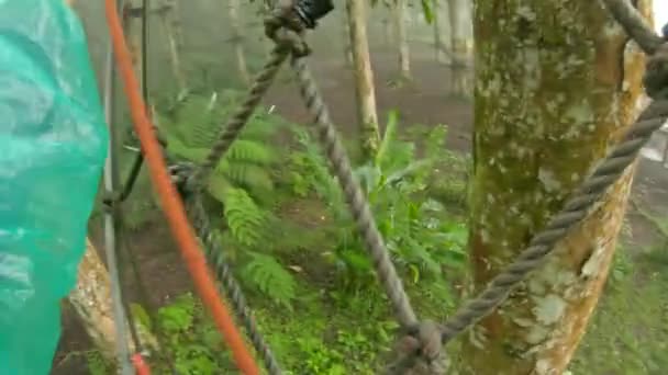 Point de vue d'un homme dans un harnais de sécurité qui grimpe sur un chemin en cime des arbres dans un parc d'aventure forestière. Il grimpe sur le sentier des hautes cordes. Centre de loisirs extérieur avec activités d'escalade 