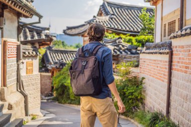 Young man tourist in Bukchon Hanok Village is one of the famous place for Korean traditional houses have been preserved. Travel to Korea Concept clipart