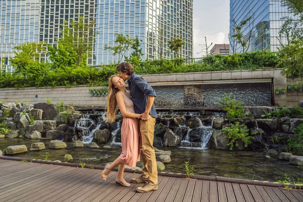 Молодая влюбленная пара проводит свой медовый месяц в Сеуле. Поток Чхонгэчхон в Сеуле, Корея. Поток Чхонгэчхон является результатом масштабного проекта обновления города. Концепция путешествия в Корею — стоковое фото