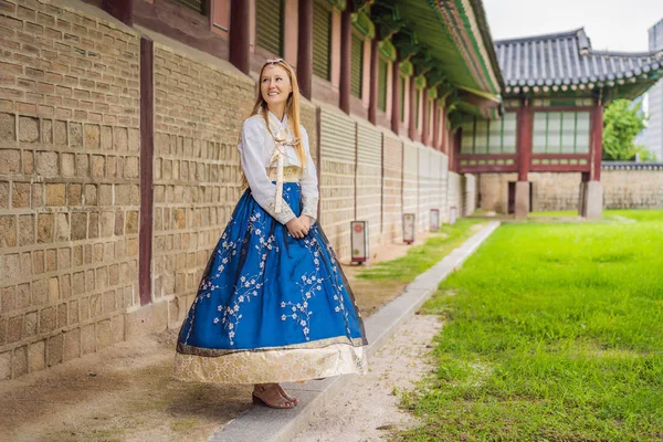 Hanbok Ulusal Kore elbisesi içinde genç beyaz kadın turist. Kore konseptine seyahat. Ulusal Kore giysileri. Turistler için eğlence - ulusal Kore kıyafetleri deniyor — Stok fotoğraf