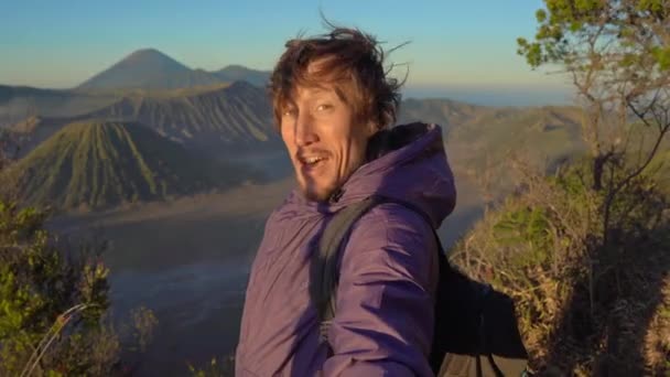 Un joven bloguero filma video selfie en el mirador del volcán Bromo dentro de la caldera Tengger en la isla Java, Indonesia — Vídeo de stock