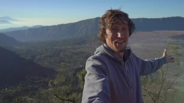 Um jovem blogueiro filma vídeo selfie no ponto de vista do vulcão Bromo dentro da caldeira Tengger na Ilha Java, Indonésia — Vídeo de Stock