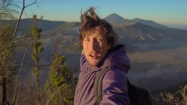 Un jeune blogueur tourne une vidéo de selfie au point de vue sur le volcan Bromo à l'intérieur de la caldera Tengger sur l'île de Java, en Indonésie — Video