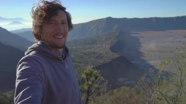 Молодой блогер снимает селфи-видео с точки зрения вулкана Бромо в кальдере Тенгер на острове Ява, Индонезия — стоковое видео