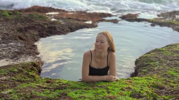 Mujer joven turista relajarse en un pequeño estanque natural con agua de mar en la playa Pantai Tegal Wangi en la isla de Bali — Vídeo de stock