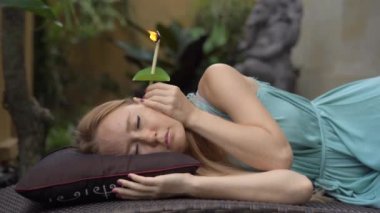 Spa'da çekici beyaz bir kadına kulak asmları yapılıyor.