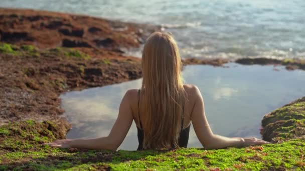 Mujer joven turista relajarse en un pequeño estanque natural con agua de mar en la playa Pantai Tegal Wangi en la isla de Bali — Vídeo de stock