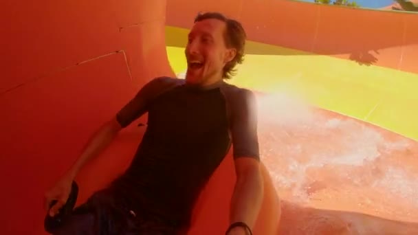Young man have fun on a water slides in an aqua park. Slowmotion video