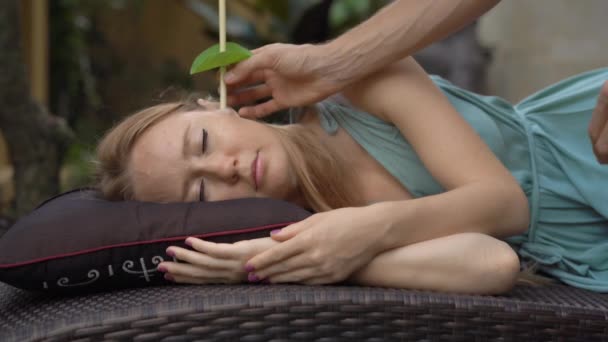 Свеча уха осуществляется на привлекательной кавказской женщине в спа — стоковое видео