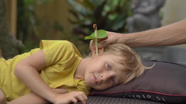 Vela de oreja que se lleva a cabo en un niño pequeño en un spa en un jardín tropical — Vídeos de Stock
