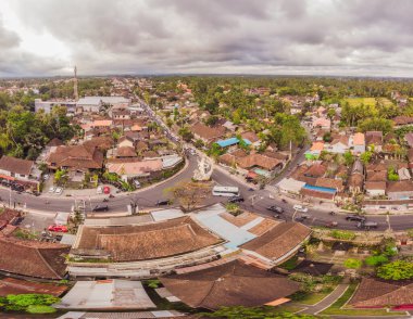 Bali 'de Ubud' da gökyüzünde tropik ağaçlar arasında kahverengi-turuncu kiremitli çatıları olan birçok villa var. Güneş üstlerinde parlıyor. Gökyüzü yatay fotoğrafı