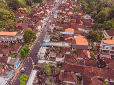 Bali 'de Ubud' da gökyüzünde tropik ağaçlar arasında kahverengi-turuncu kiremitli çatıları olan birçok villa var. Güneş üstlerinde parlıyor. Gökyüzü yatay fotoğrafı