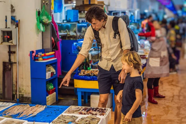 Отец и сын на корейском рынке. Сырые морепродукты на оптовом рынке Норянджин в Сеуле, Южная Корея. Путешествие с детьми, концепция — стоковое фото