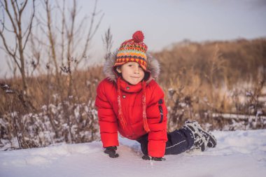 Kırmızı elbiseli çocuk dışarıda oynuyor. Soğuk günlerde kışın çocuklarla aktif bir eğlence. Çocuk ilk karla eğleniyor. Mutlu küçük çocuk karda oynuyor, güzel kış havası