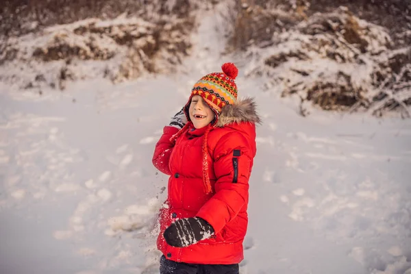 Garçon en vêtements de mode rouge jouant à l'extérieur. Loisirs actifs avec les enfants en hiver par temps froid. Garçon s'amuser avec la première neige. Joyeux petit enfant joue dans la neige, beau temps d'hiver — Photo