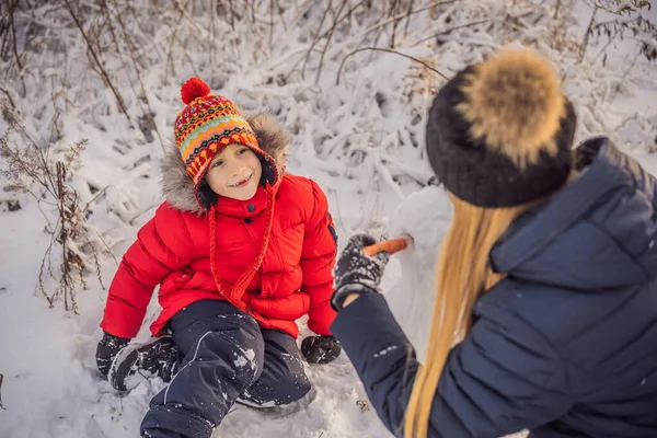 따뜻한 옷에 행복 한 가족입니다. 어머니와 아들 야외 눈사람을 만드는 미소. 겨울 활동의 개념 — 스톡 사진