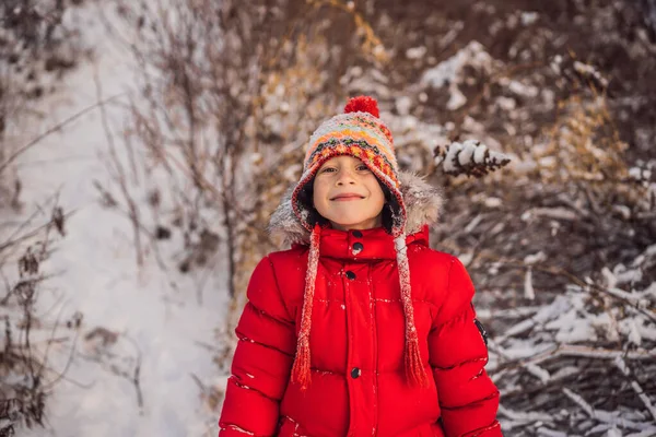 Pojke i röda kläder som leker utomhus. Aktiv fritid med barn på vintern under kalla dagar. Pojken har kul med första snön. Glad liten unge leker i snö, bra vinterväder — Stockfoto