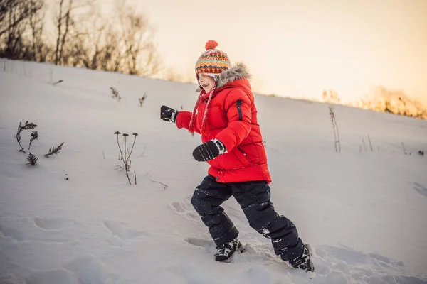 Симпатичний хлопчик в червоному зимовому одязі біжить весело на снігу. Зимові веселощі Відкриті концепції — стокове фото