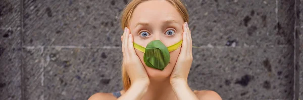 Frau machte sich eine Gesichtsmaske aus den Blättern, um sich vor Luftverschmutzung zu schützen. Luftreinigungskonzept. Bäume reinigen das Luftkonzept Banner, langes Format — Stockfoto