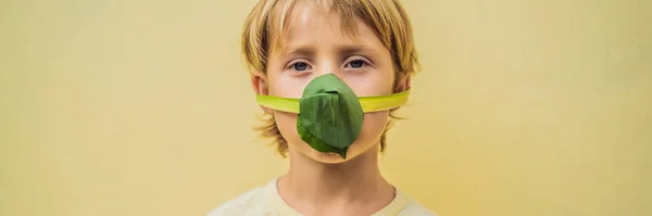A gyermek arcmaszkot készített magának a levelekből, hogy megvédje magát a légszennyezéstől. Levegőtisztítás a gyermekek számára. A fák tisztítják a levegő koncepcióját Banner, Long Format — Stock Fotó