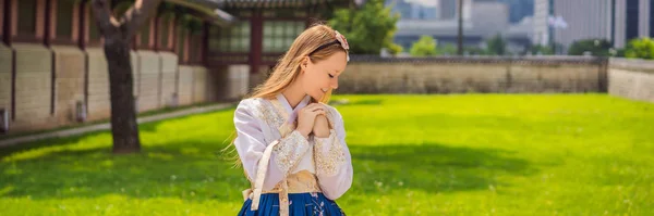 Hanbok Ulusal Kore elbisesi içinde genç beyaz kadın turist. Kore konseptine seyahat. Ulusal Kore giysileri. Turistler için eğlence - ulusal Kore giyim bayrağı deneniyor, Long Format — Stok fotoğraf